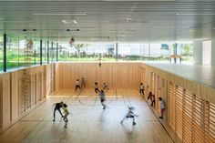 an indoor basketball court with people playing on the floor and in the background are windows