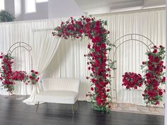 red flowers are growing on the side of a white stage set up for a wedding ceremony