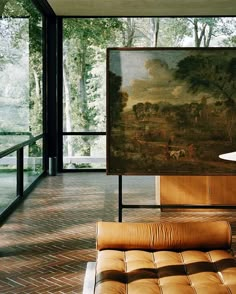 a living room with a painting on the wall and leather furniture in front of it