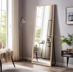 a large mirror sitting on top of a wooden floor next to a chair and table