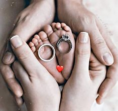 two people holding their hands with wedding rings on top of them and a red heart in the middle