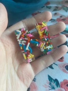 a person is holding some kind of colorful object in their hand with sprinkles on it