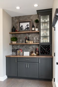 a bar with wine glasses and bottles on the top shelf, next to a door