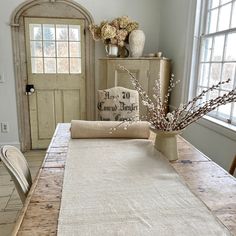 a dining room table with an old door in the back ground and flowers on top