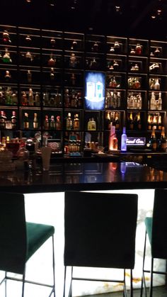 the bar is full of liquor bottles and empty chairs in front of an illuminated television