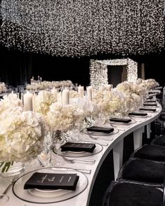 a long table is set with white flowers and candles for an elegant dinner or party