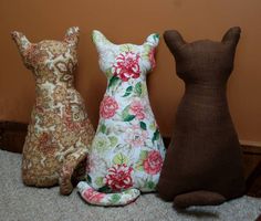 three stuffed animals sitting next to each other on the floor in front of a wall