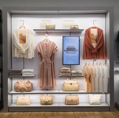 a display case filled with lots of women's clothing and handbags on shelves