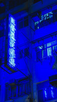 an illuminated sign on the side of a building at night with blue lights in the windows