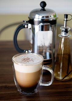 a cappuccino sits on a table next to a coffee pot and carafe