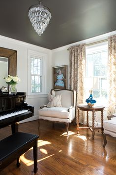 a living room filled with furniture and a chandelier hanging from the ceiling over a piano