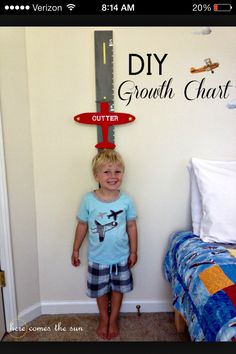 a young boy standing in front of a growth chart on the wall next to a bed