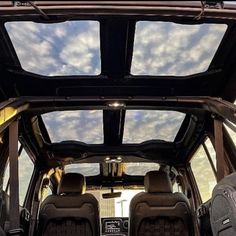 the interior of a vehicle with seats up and sky in the background