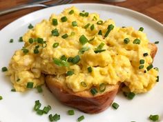 scrambled eggs on toast with chives on a white plate