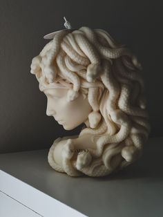 a sculpture of a woman's head on top of a shelf next to a wall