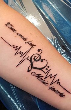 a heartbeat tattoo on the arm with music notes