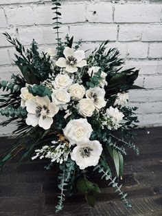 white flowers and greenery are arranged in a vase