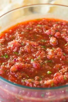 a glass bowl filled with salsa and tortilla chips on top of a table