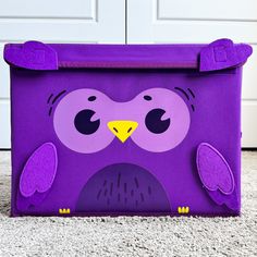 a purple bag with an owl design on the front and bottom, sitting on carpet