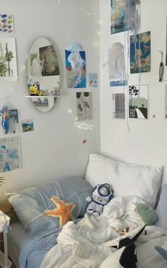 an unmade bed in a white room with pictures on the wall and decorations around it