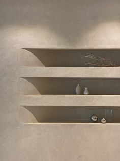 three white vases sitting on top of a shelf next to each other in a room