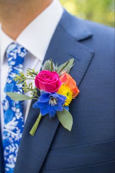 a man wearing a blue suit and colorful boutonniere