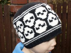 a young boy wearing a black and white knitted beanie with skulls on it