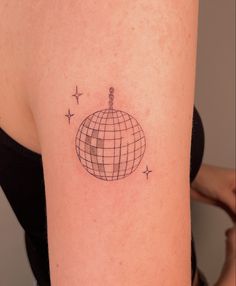 a woman's arm with a small tattoo of a ball and stars on it