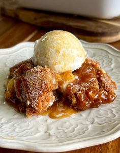 a white plate topped with an ice cream and apple cobbler next to a wooden table