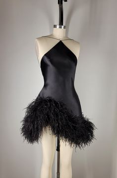 Fin  Black silk sueded satin backless halter, tapered neckline suspended by dainty satin cord. Asymmetrical hem embroidered with custom dyed pure ostrich feathers. Invisible zipper at center back.    Color and length may be customized. May be paired with custom designed sleeves and gloves. FAQS HOW LONG DOES THE PROCESS TAKE? Each look is custom made to order with precise measurements. Ideally requiring a minimum of 8 weeks.  If faster delivery is needed, a priority reservation can be placed with this listing: https://www.etsy.com/listing/1606891070/priority-reservation WHAT MEASUREMENTS ARE REQUIRED?  Your unique measurements are the most important part of the process. These measurements will be needed to begin work on your garment. * BUST (Around the fullest part of the chest, including Formal Mini Dress Outfit, Futuristic Glam Outfit, Satin Birthday Outfit, Black Salsa Dress, Waist Drop Dress, Edgy Cocktail Attire, Custom Made Birthday Dress Black Women, Asymmetrical Mini Dress, Ostrich Feather Outfit