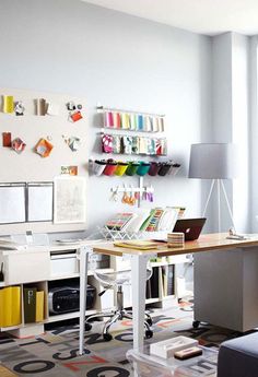 a room with a desk, chair and shelves filled with crafting supplies on the wall