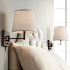 a bed with two lamps on either side of the headboard and one light is turned on