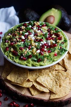 a white bowl filled with guacamole surrounded by tortilla chips