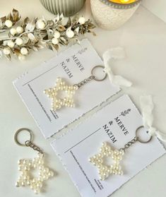 two key chains with pearls on them sitting next to some flowers