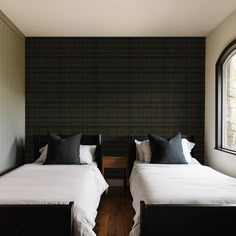 two beds in a room with black and white wallpaper