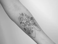 a black and white photo of a woman's arm with flowers on it in the shape of a heart