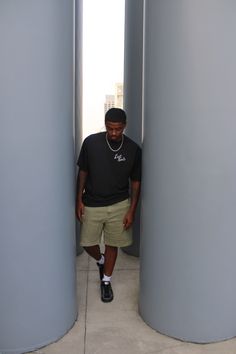 a man is standing between two large gray pillars and looking down at the ground below