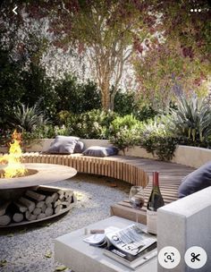 an outdoor fire pit surrounded by trees and rocks, with seating around the firepit