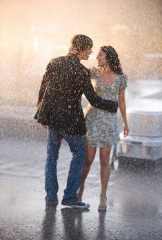 a man and woman standing under an umbrella in the rain with their hands around each other