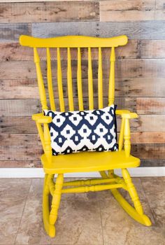 a yellow rocking chair with a black and white pillow