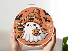 someone holding up a cross - stitch halloween ghost