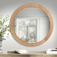 a round mirror sitting on top of a wooden table next to a vase filled with flowers