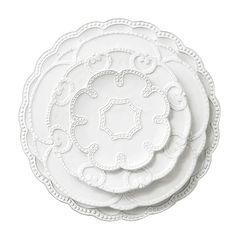 four white plates stacked on top of each other with ornate designs in the middle and bottom