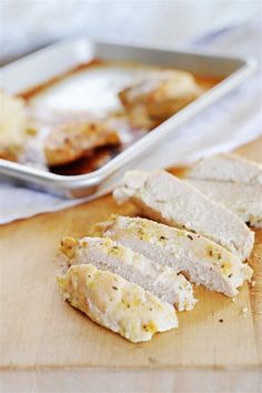 slices of chicken on a cutting board next to a pan of bread and sauces