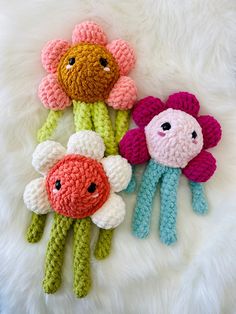 three crocheted stuffed animals sitting next to each other on a white fur surface