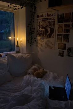 a laptop computer sitting on top of a bed in a room with white sheets and pillows