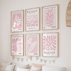 four pink and white prints hang on the wall above a bed in a room with pillows