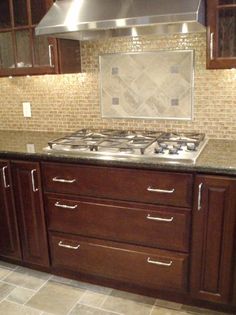 a stove top oven sitting inside of a kitchen next to wooden cabinets and counter tops