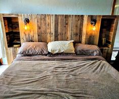 a bed made out of wood with two lights on each side and one light at the headboard