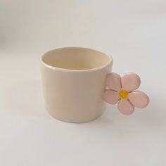 a white cup with a pink flower sticking out of it